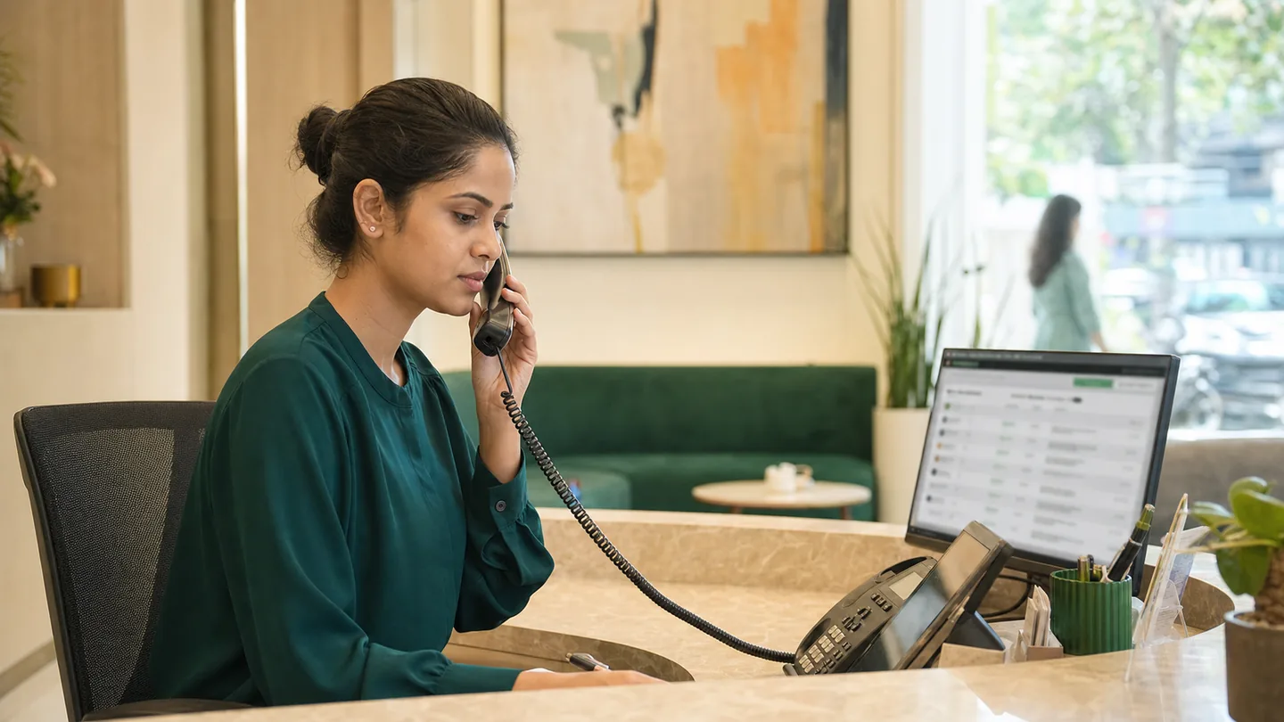 Patient follow-up और recall system कैसे बनाएँ: a front-desk professional working through a structured call and message follow-up list.